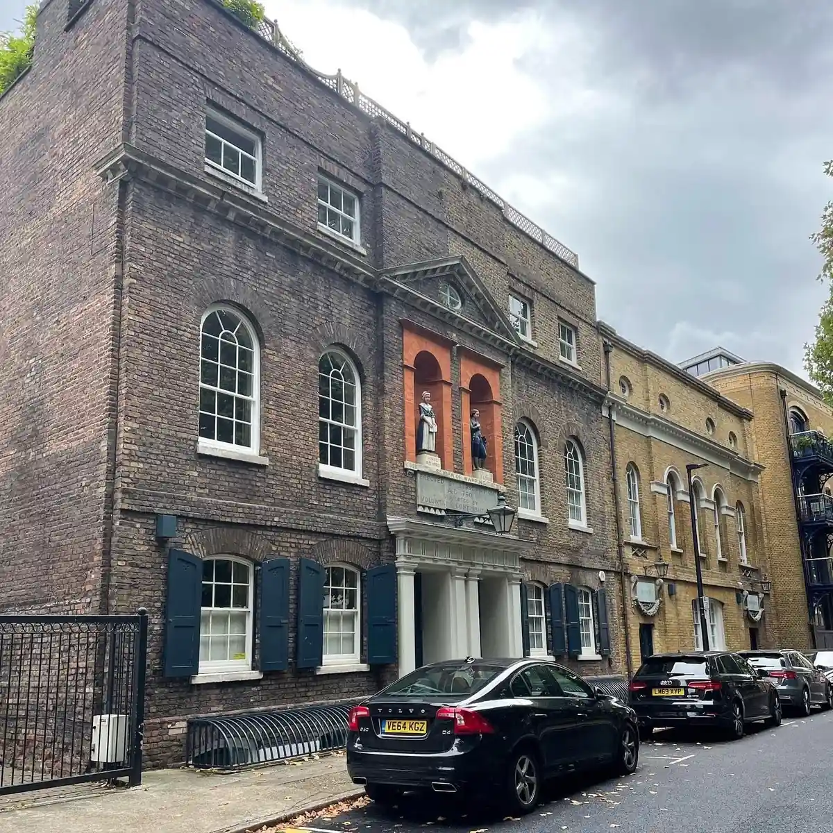 A Grade II listed brick warehouse building in Wapping with arched sash windows and shutters