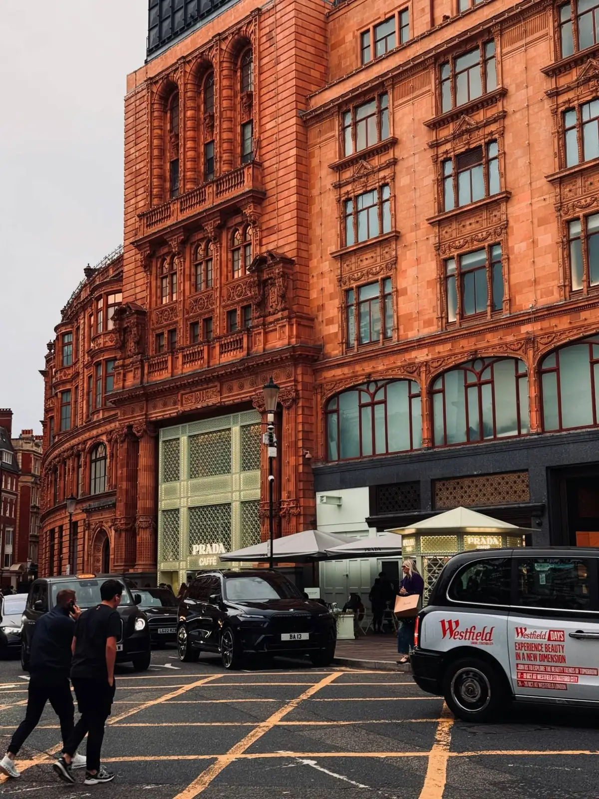 An ornate terracotta department store facade with tall timber-framed windows above a busy Knightsbridge street