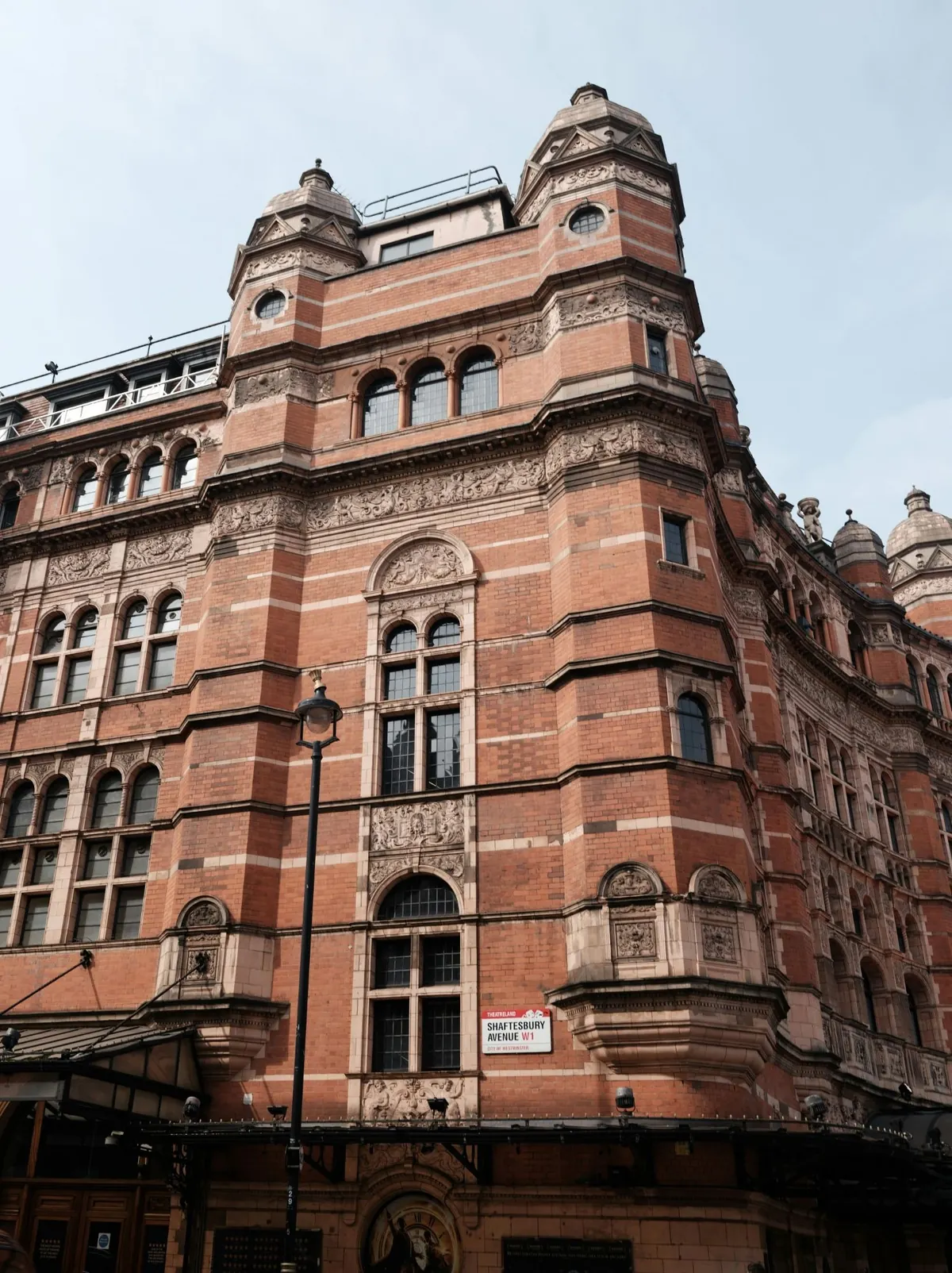 A late-Victorian red-brick and terracotta theatre on Shaftesbury Avenue, with corner turrets and tall arched windows