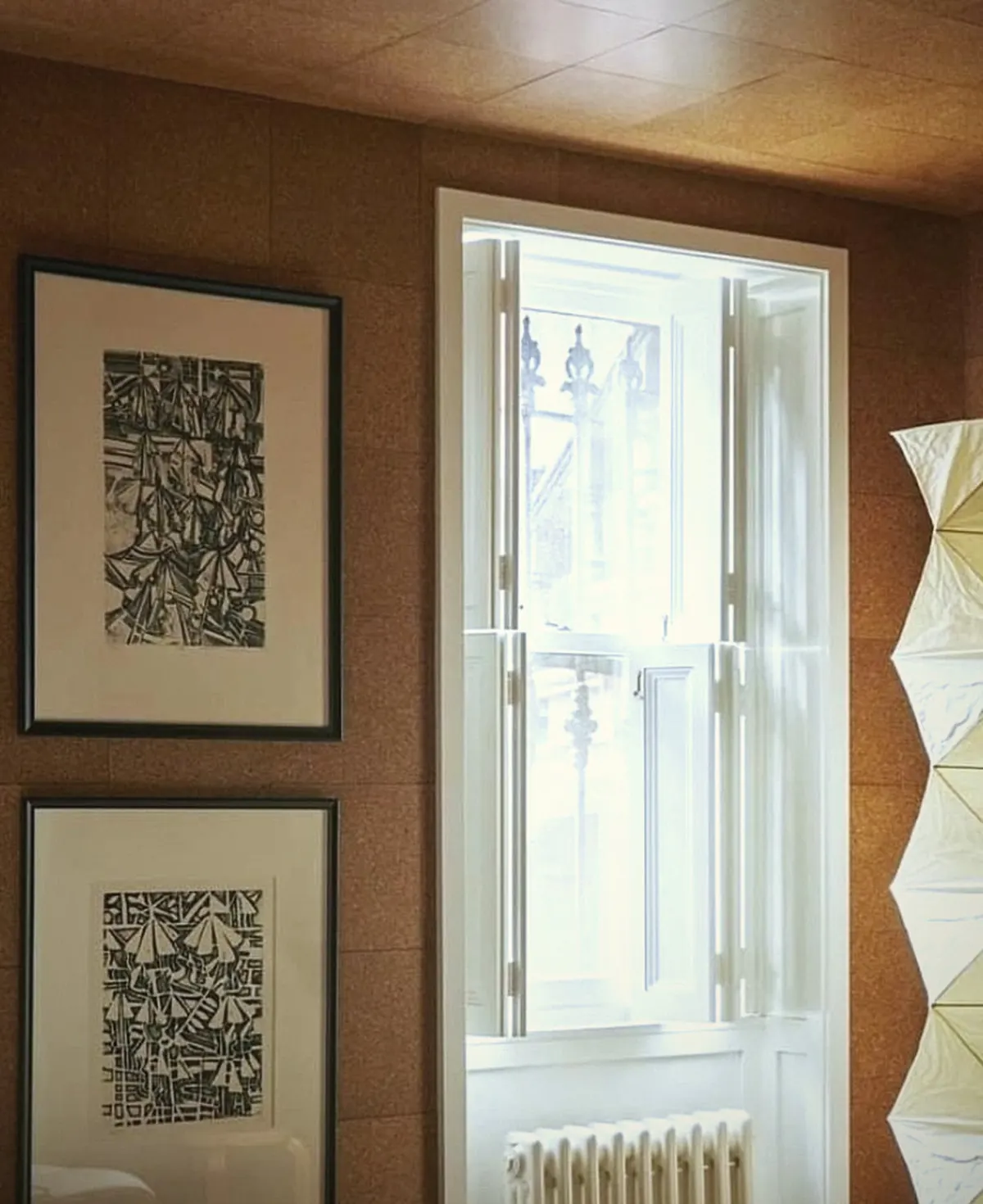 A sash window between framed prints in a warm-toned room