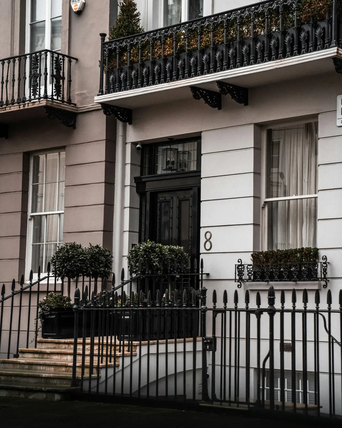 A stucco-fronted townhouse with a black door, cast-iron balcony and sash windows