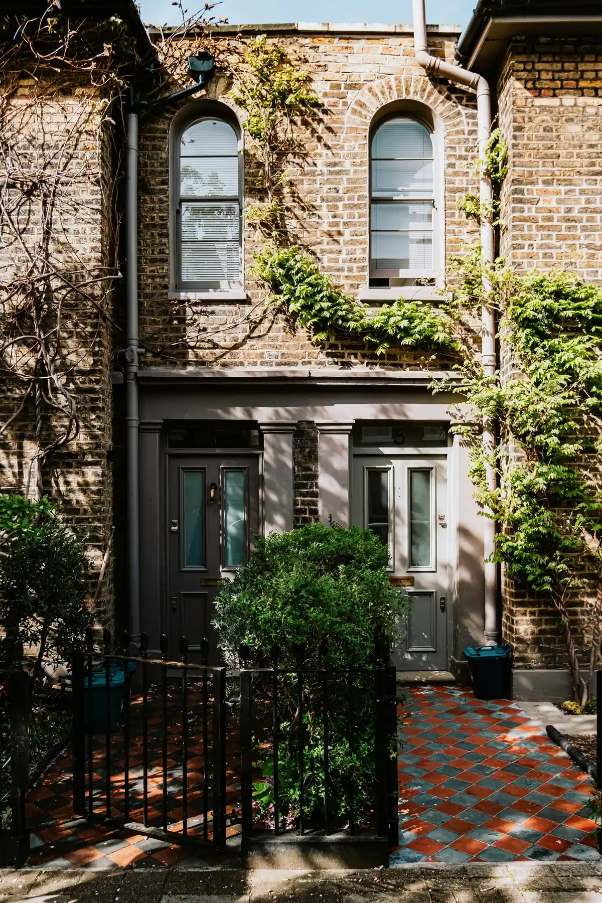 A Victorian stock-brick terrace with arched sash windows and climbing wisteria