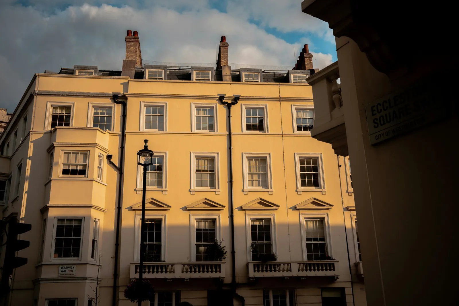A cream stucco terrace in golden evening light with sash windows and balustrades