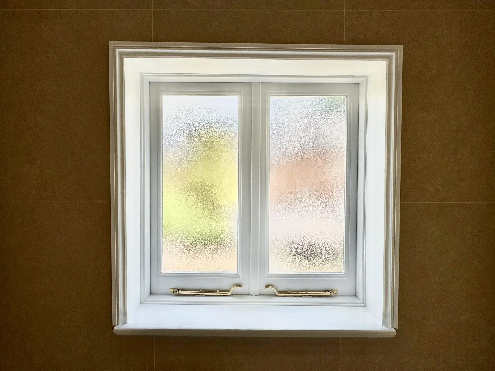 A white timber casement window, closed, set in a deep reveal