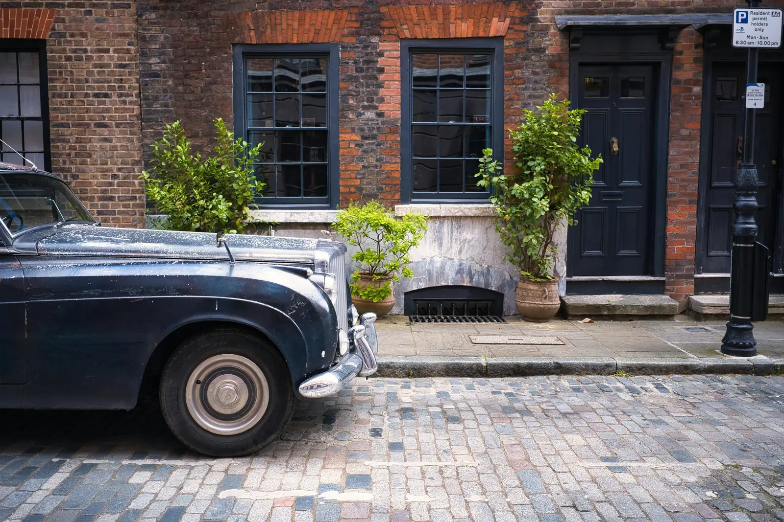 A Georgian brick terrace with dark-painted sash windows and panelled doors on a cobbled street