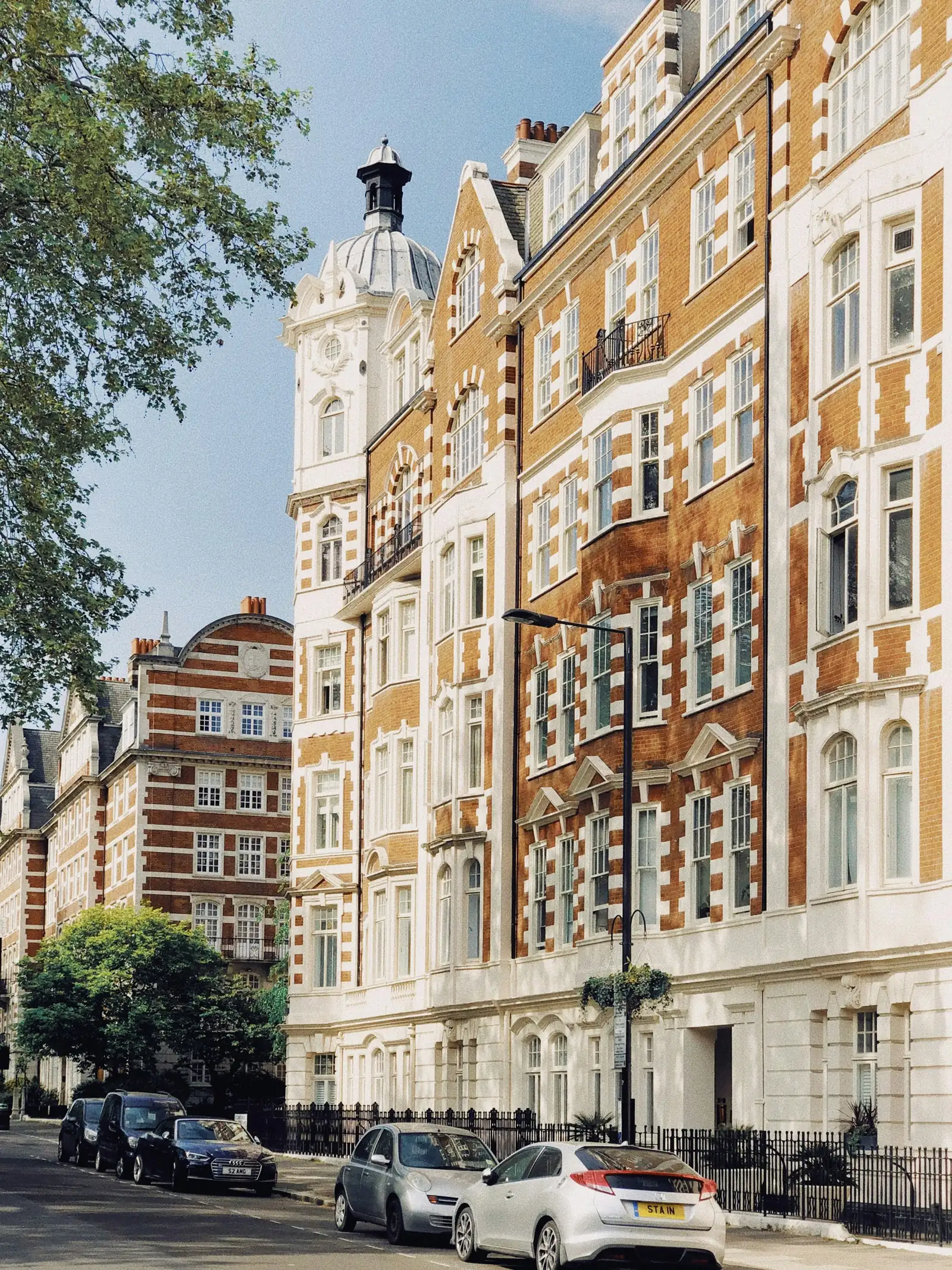 Red-brick and white stone mansion blocks with tall timber sash windows and a domed corner turret