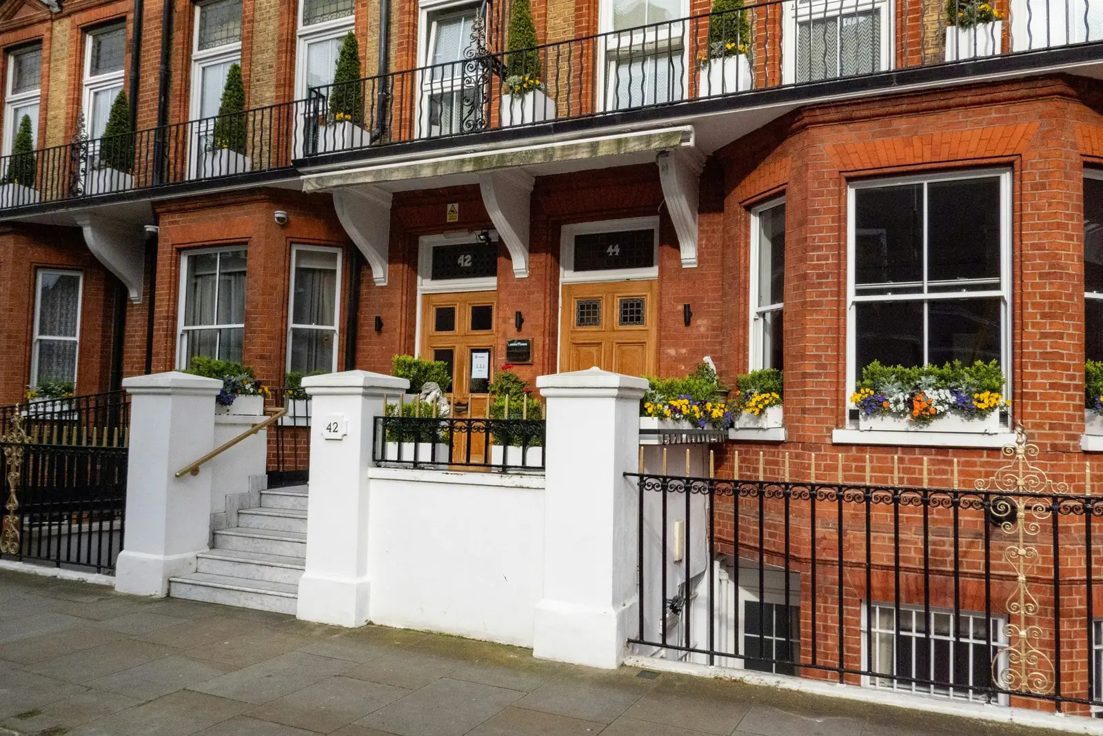 A red-brick Victorian mansion terrace with white piers, railings and sash windows