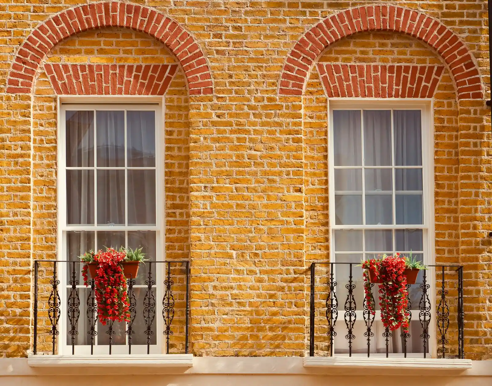 Two tall six-over-six sash windows in yellow stock brick under red gauged-brick arches