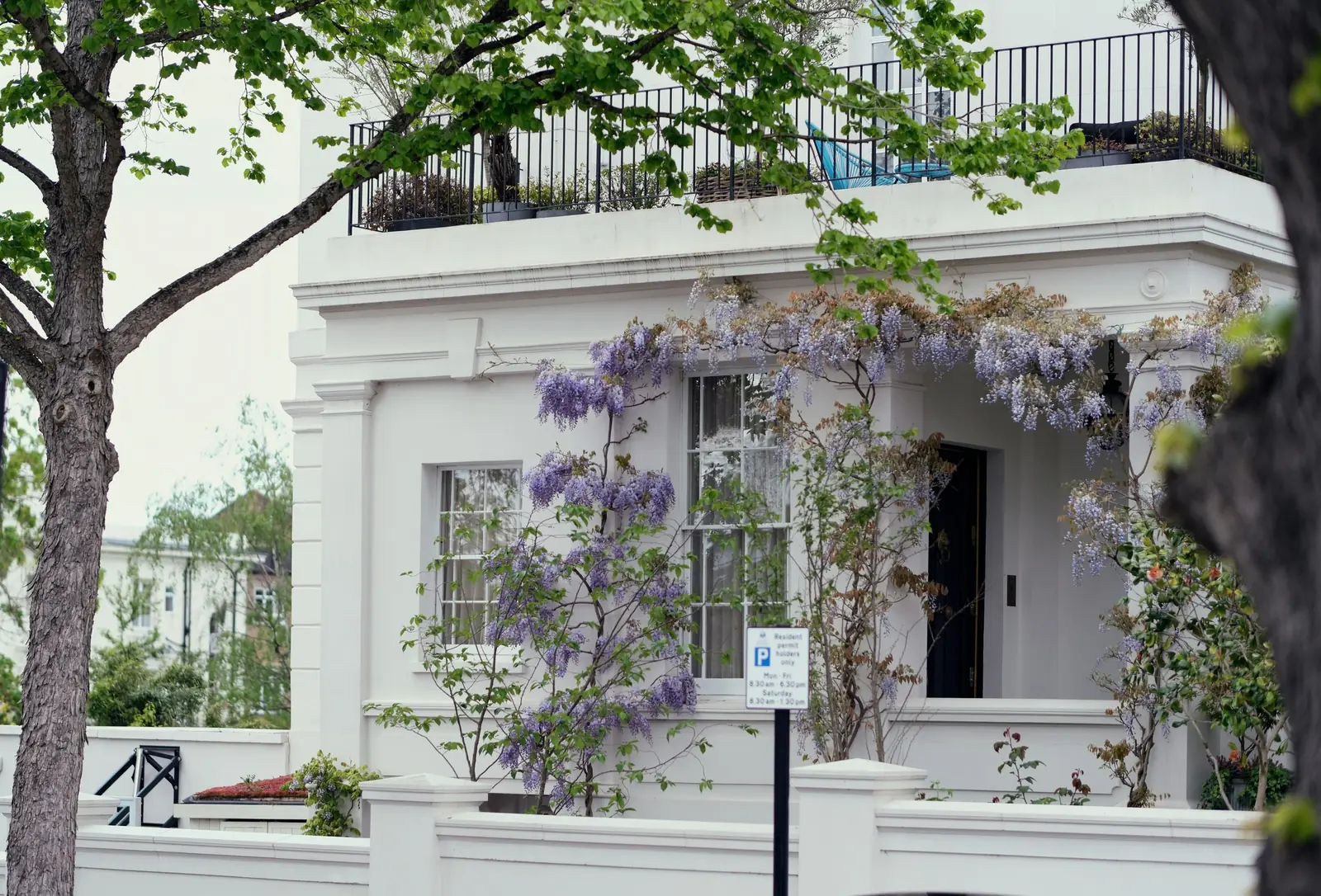 A white stucco villa porch hung with wisteria, with sash windows above