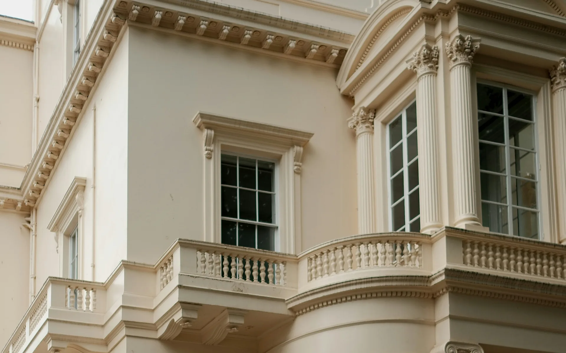 Cream Regency stucco with a bow window, Corinthian pilasters and a balustraded balcony