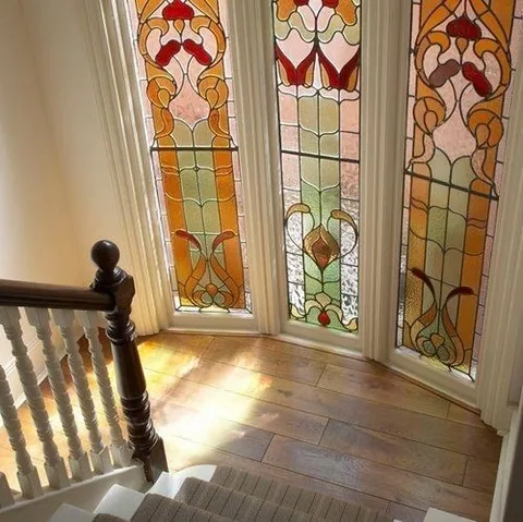 Tall stained-glass windows lighting a staircase landing