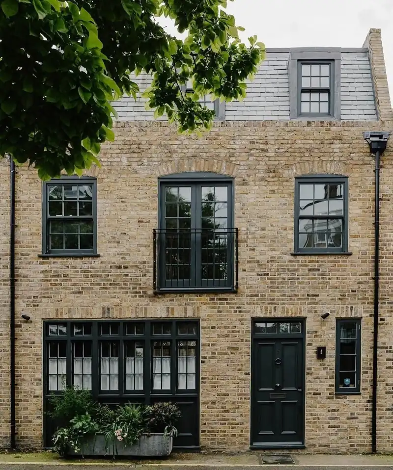 A London stock-brick mews house with dark-painted timber sash windows