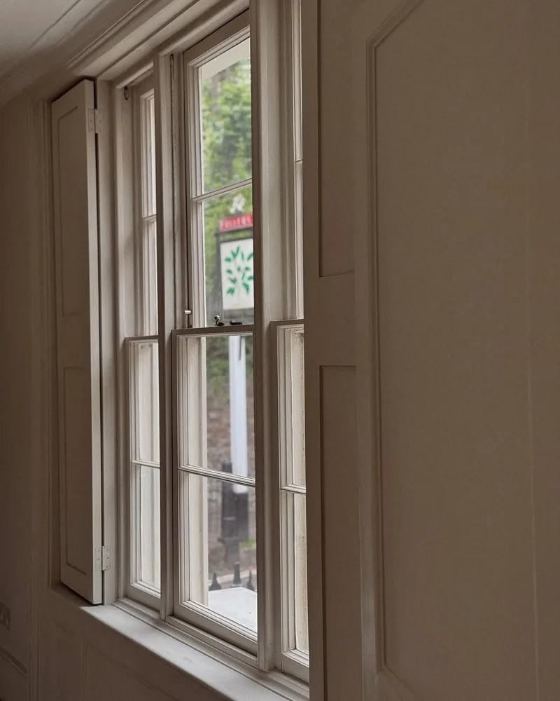 A tall timber sash window set in a deep panelled reveal