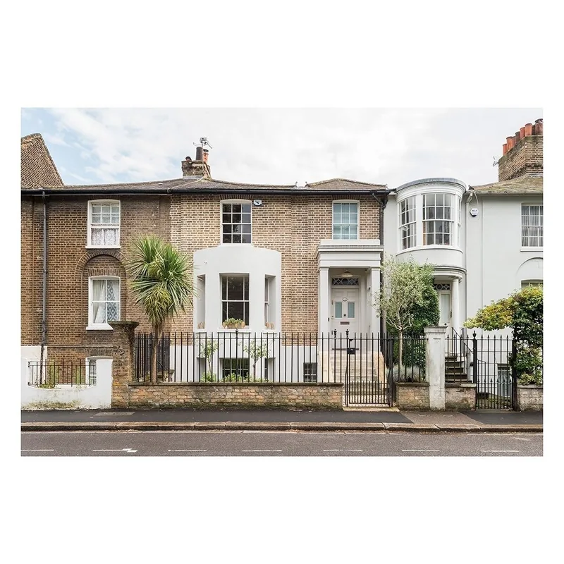 A row of Victorian terraced houses with timber sash windows behind front gardens