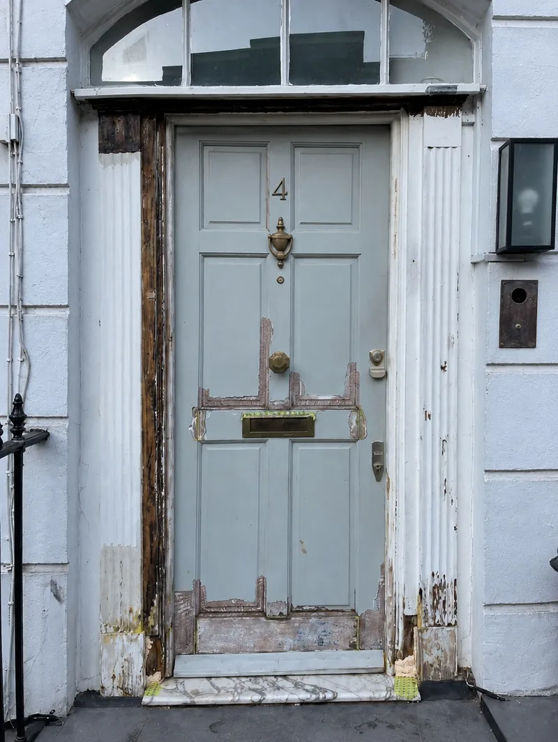 The same door before the work, with peeling paint and a damaged bottom rail and frame