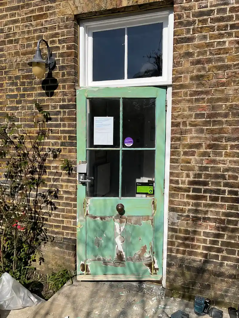 The same door before the work, with weathered and peeling green paint